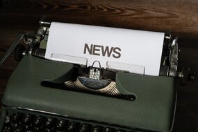 Old green typewriter with a paper in it, stating "news"