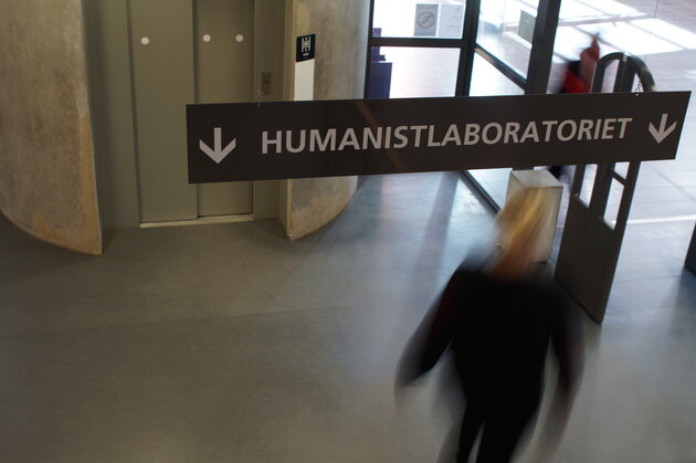 sign ahnging from roof saying "Humanitslaboratoriet" with a blurry person behind