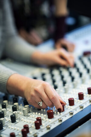two hands on a sound mixerboard