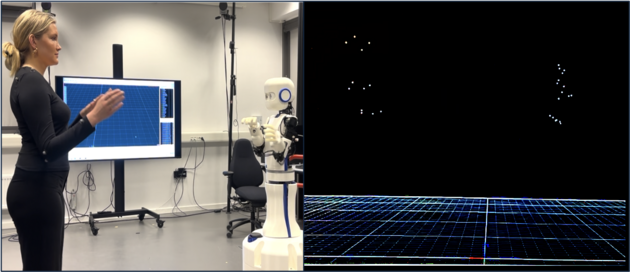 woman gesturing in fron of a robot and a screen with motion capture data