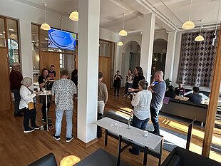[Translate to English:] people gathering inside a room with high cealing and columns