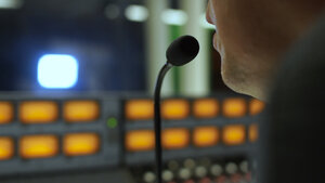 man speaking in microphone in front of sound mixer