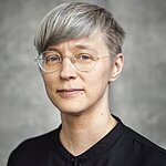 Splendido is a white person wiht short hair and transparent glasses. They are looking directly into the camera.