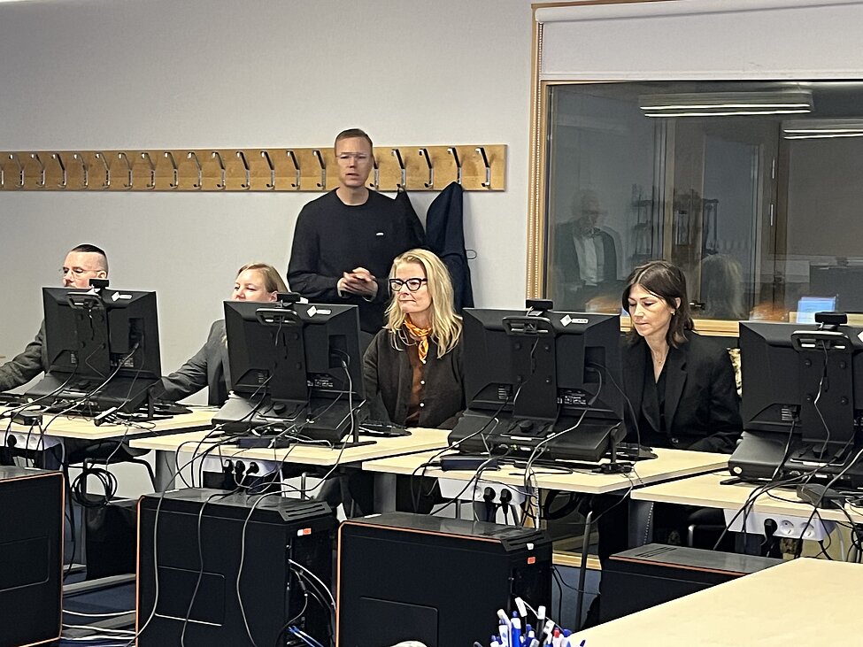 [Translate to English:] people sitting behind computers in a classroom