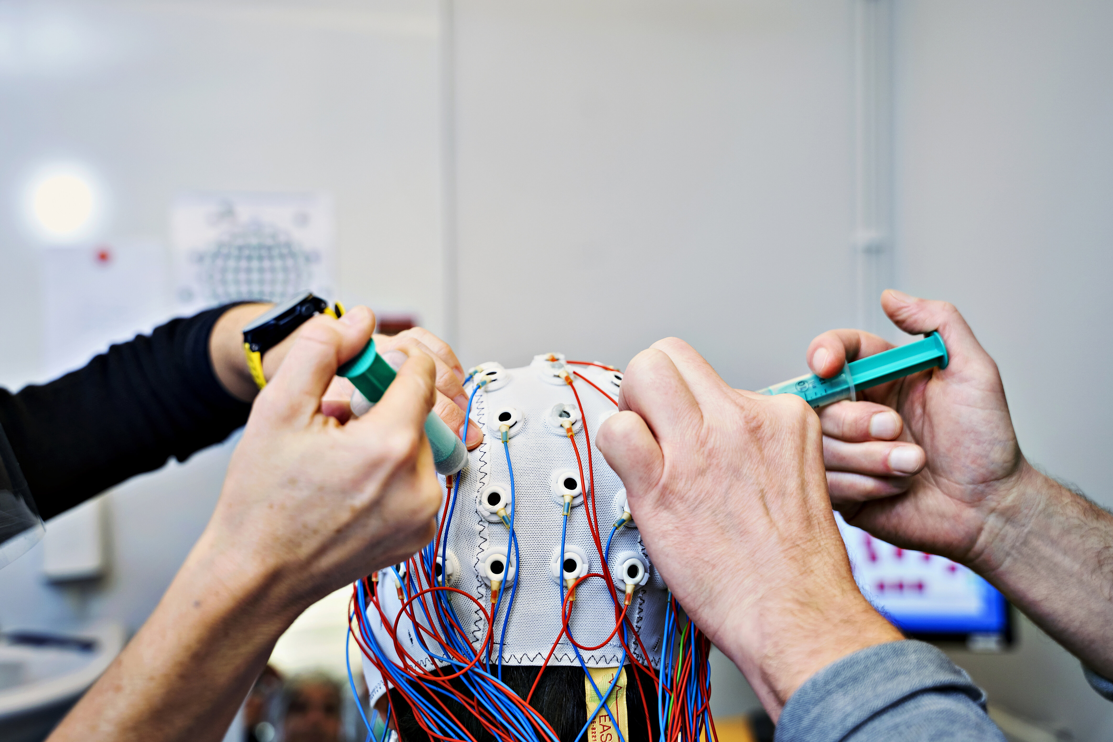 two sets of hands working with the top of a eeg-cap