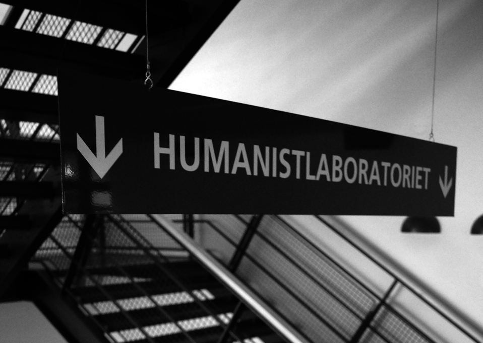 [Translate to English:] Black and white picture with sign hanging over stairs with the word "Humanitlaboratoriet" on it.