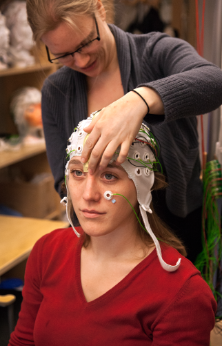 one person is putting on a EEG cap and electrodes on another person