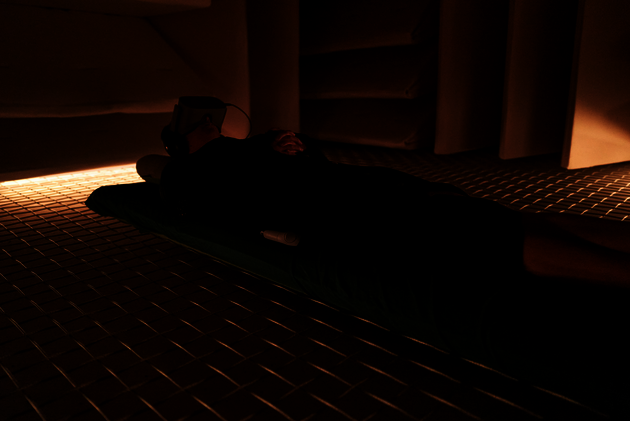 person lying on floor in a low lit room wearing a VR headset