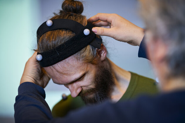 one person is putting a headband with mocap markers on the head of another person