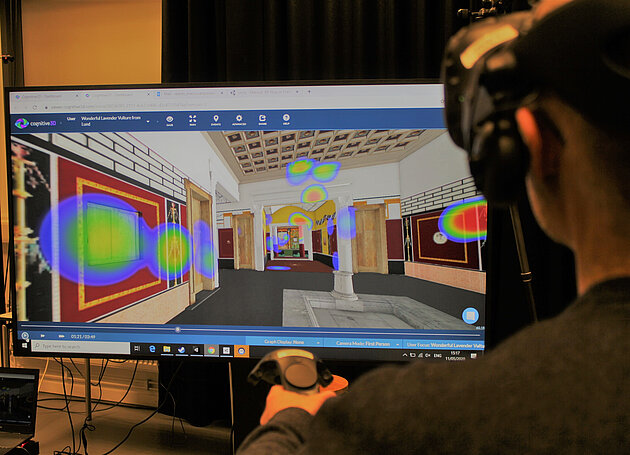 person with VR-headset in front of screen with heat map