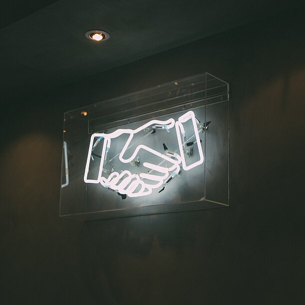 neon sign of a handshake with black background