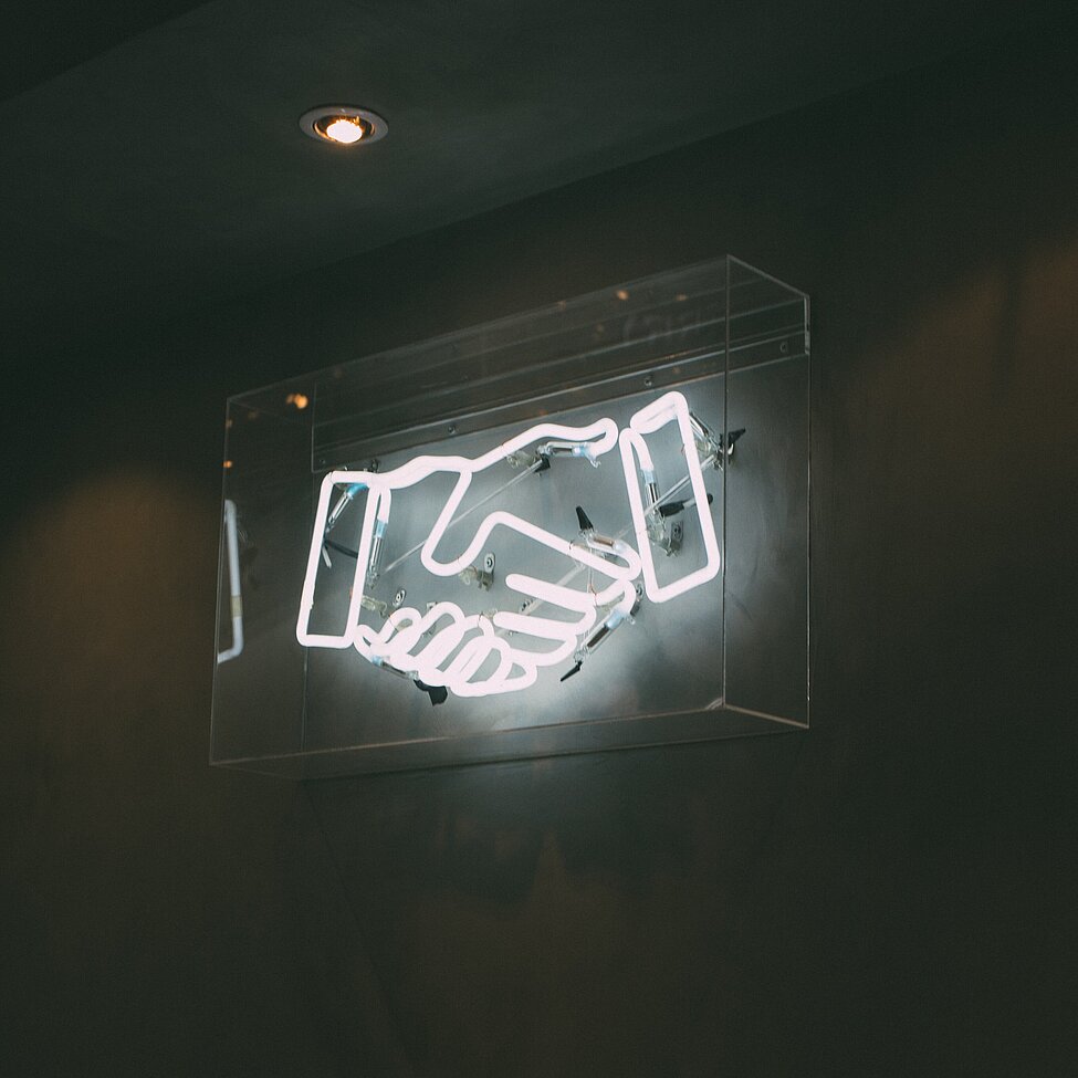 neon sign of a handshake with black background