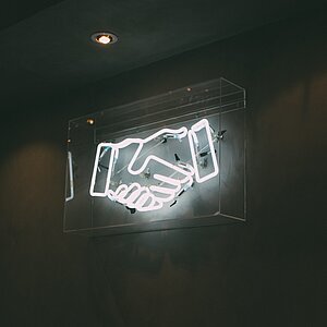 neon sign of a handshake with black background