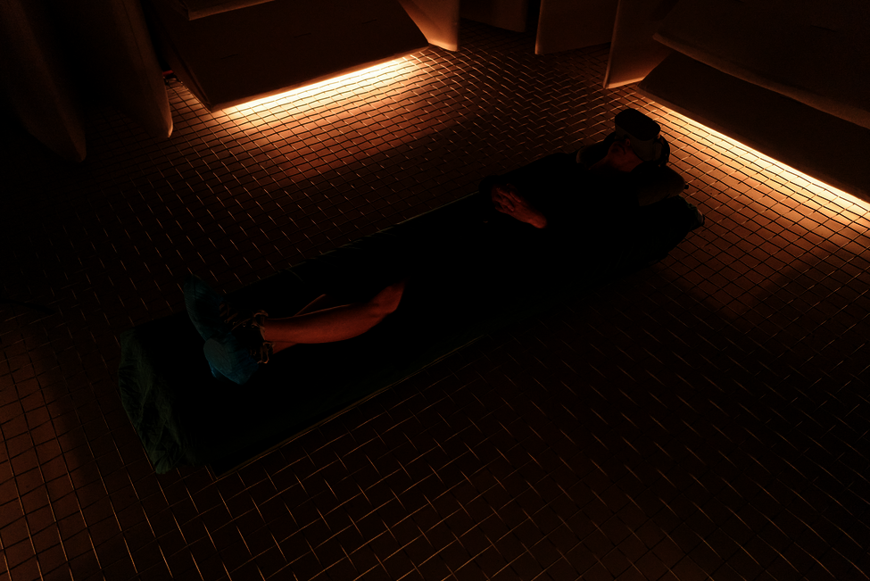 person lying in a low lit room on the floor wearing a VR-headset